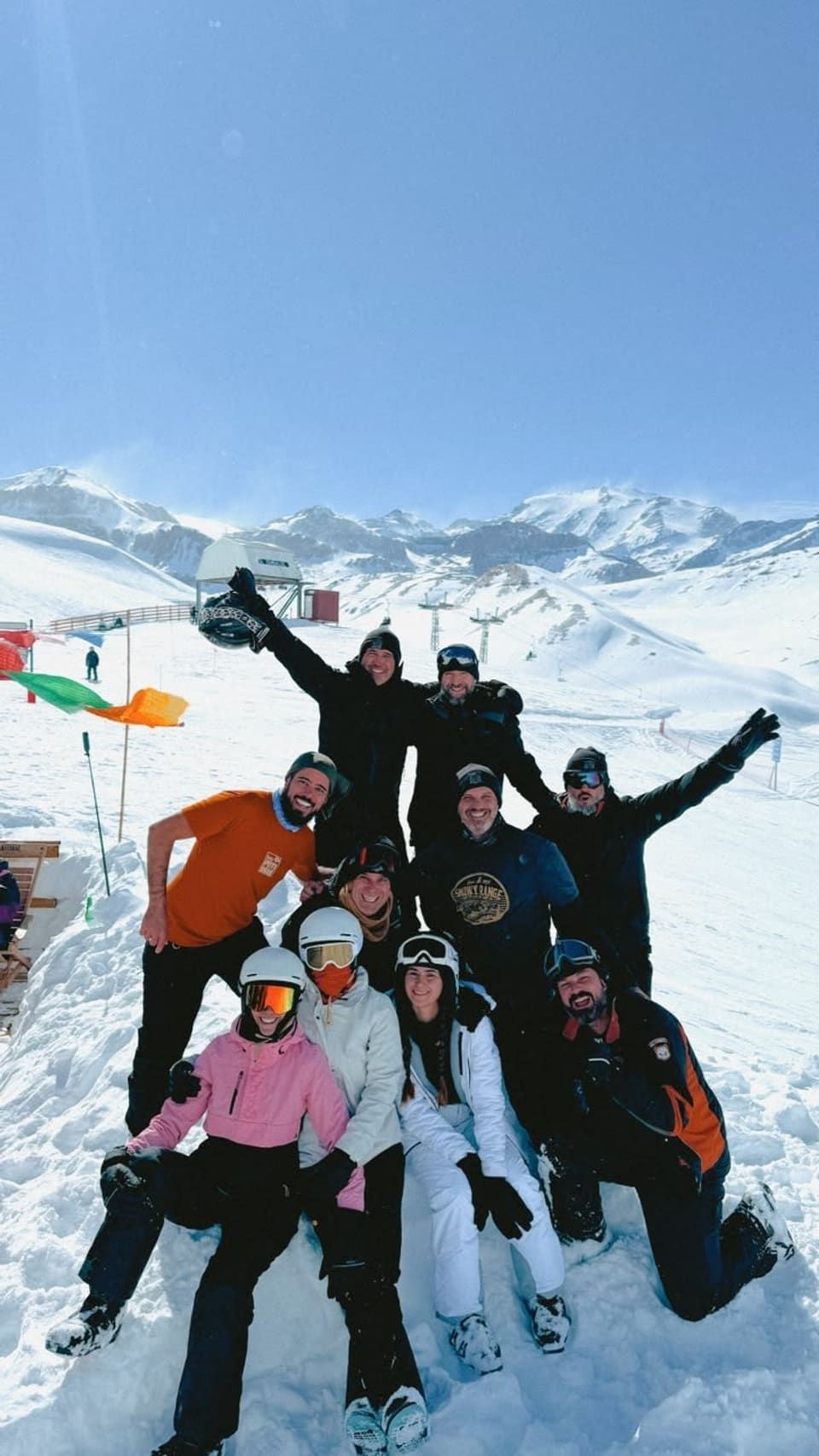 Grupo de dez amigos reunidos na neve do Valle Nevado, com a cordilheira e o teleférico ao fundo